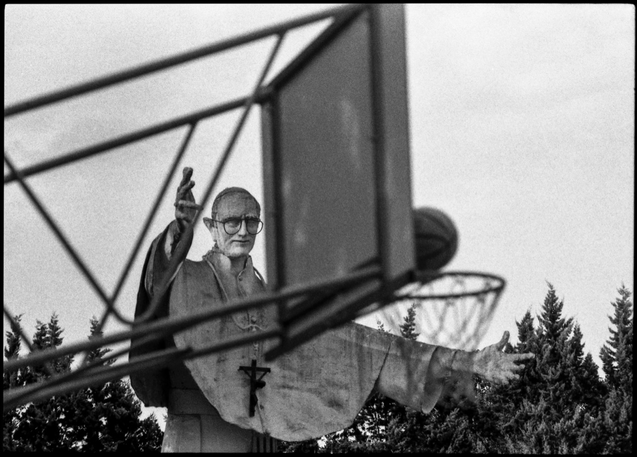 Giovanni Peyrone Roma fotografia in bianco e nero di statua di papa dietro a canestro di basket