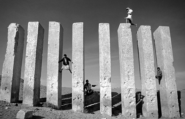 Voghera fotografia 2022 sulle orme di Pasilini foto in bianco e nero con gruppo di ragazzi arrampicati su enormi piloni quadrati di cemento