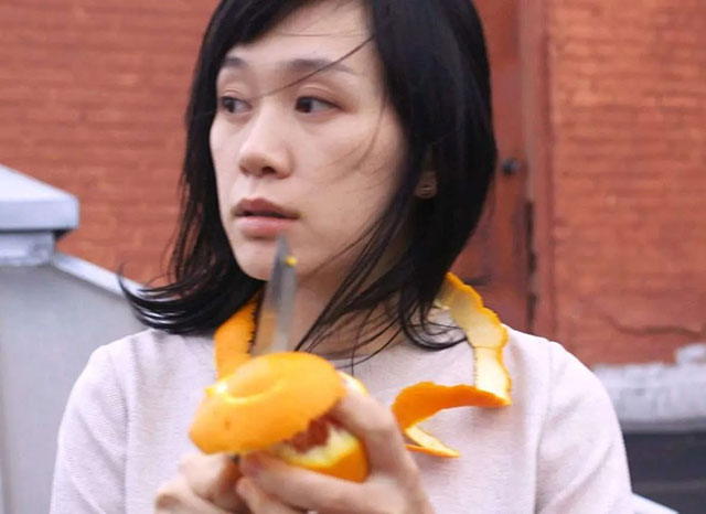 Erin Johnson Roma foto a colori di ragazza asiatica che sbuccia un'arancia con un coltello