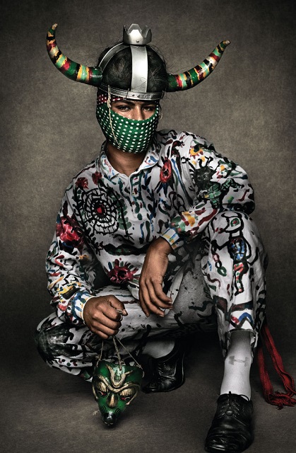 Mario Testino Roma foto a colori di giovane con vestito colorato e copricapo con corna e mascherina sul volto